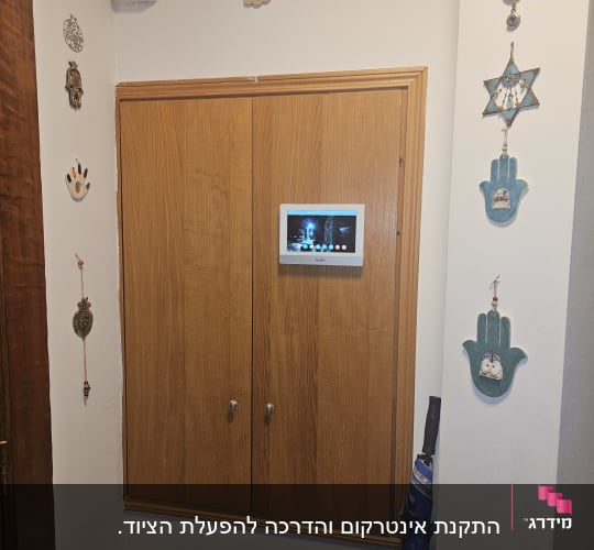 מסך אינטרקום מותקן על קיר עם קישוטים סביבו
